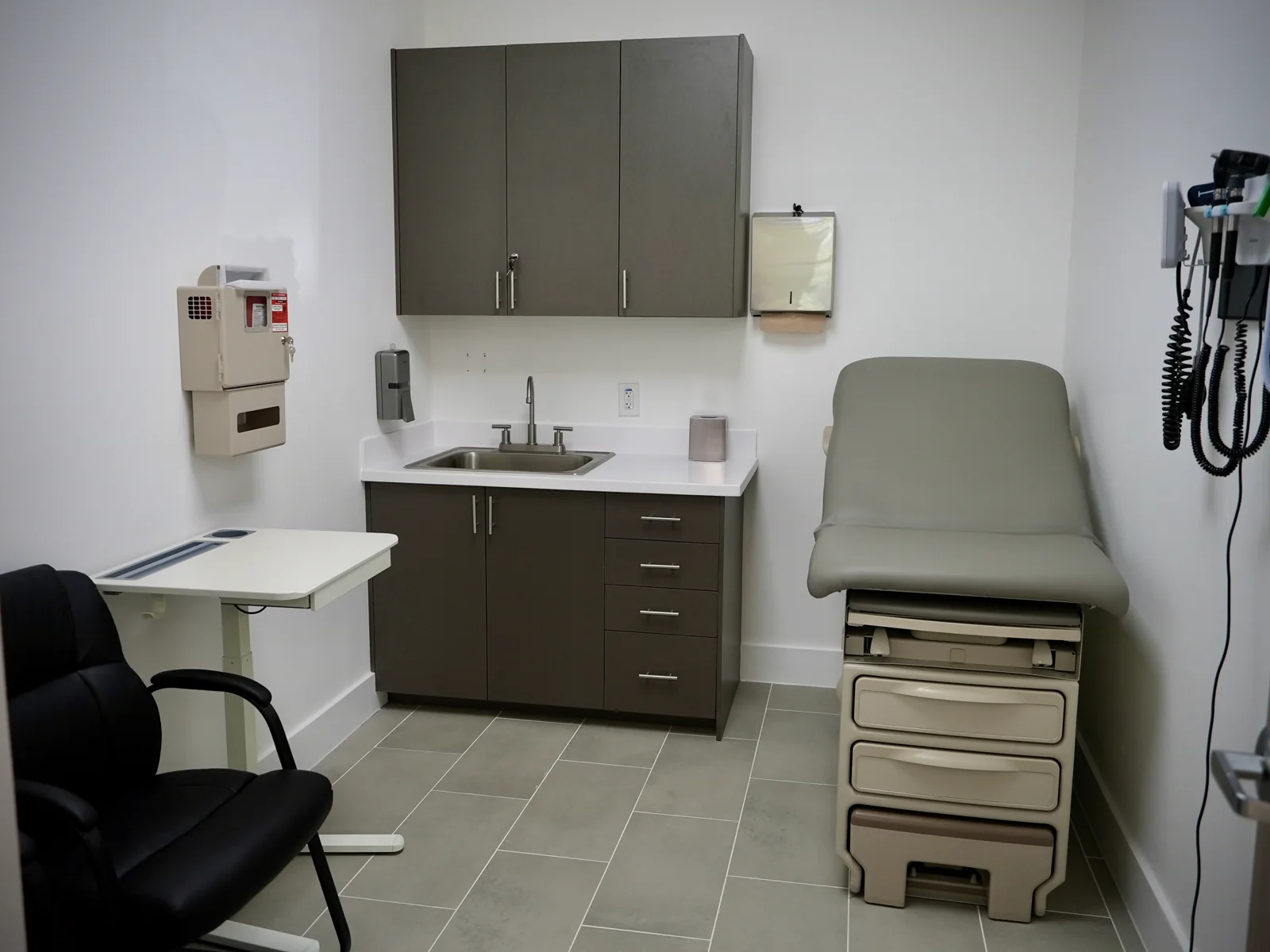 Medical exam room with wall cabinets, base cabinets, worktop, and sink